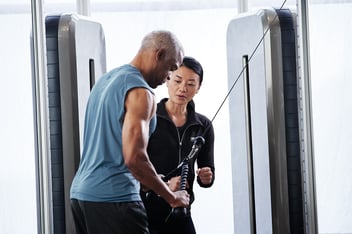 female trainer helping client on lat pull down machine