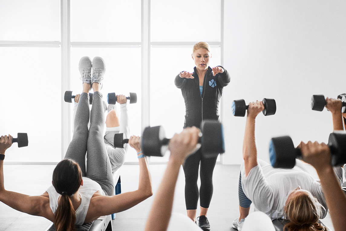 group fitness trainer in burn class with dumbbells